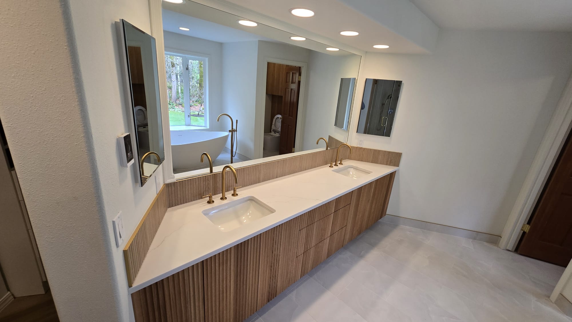 Wall-to-wall bathroom mirror above a wood vanity