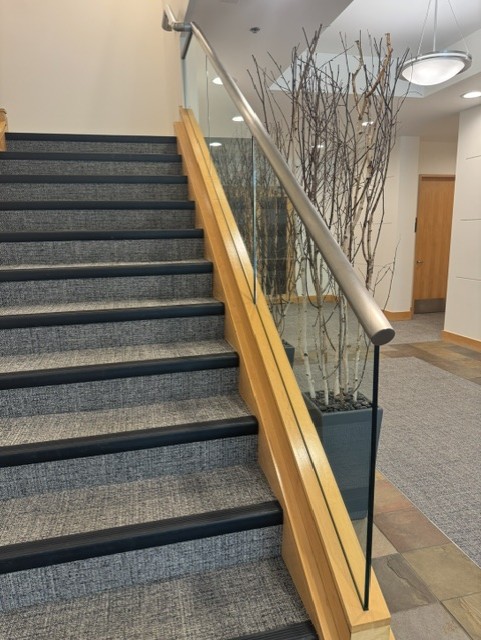 Glass stair railing with wood trim and metal handrail