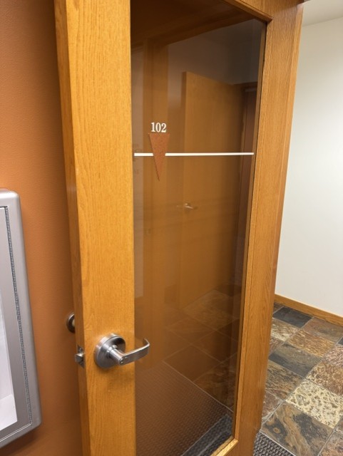 Wood-framed glass office door with room number